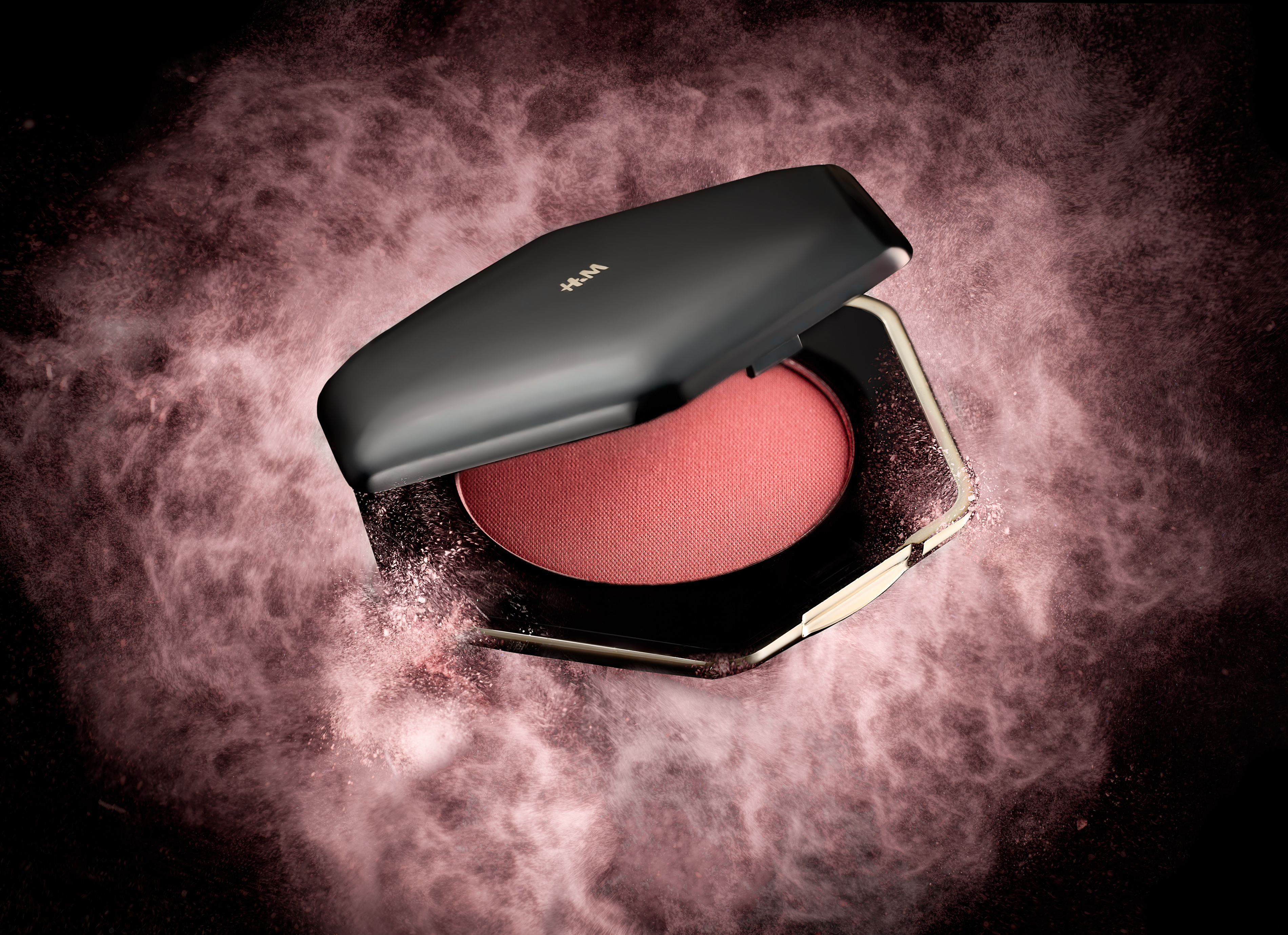 Open H&M blush compact with pink powder against a textured rose-coloured background.